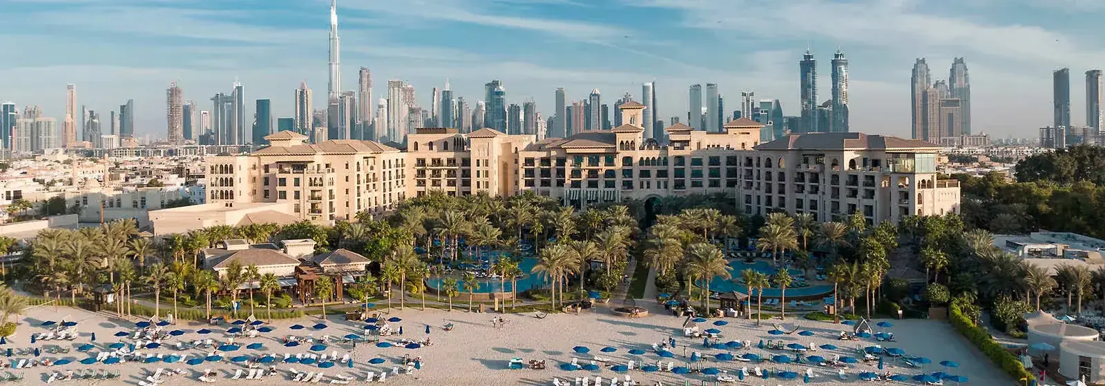 Aerial view of Four Seasons Dubai beachfront resort with private beach, pool, palm trees and Dubai skyline — ALMAS Hospitality luxury development consulting
