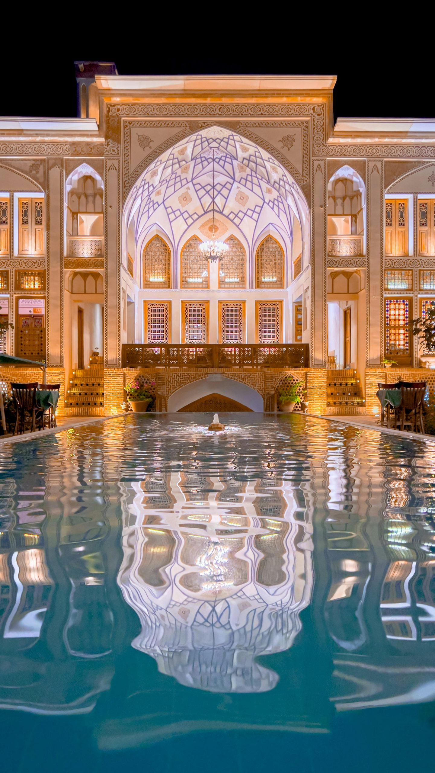 Grand luxury hotel courtyard with reflecting pool at night
